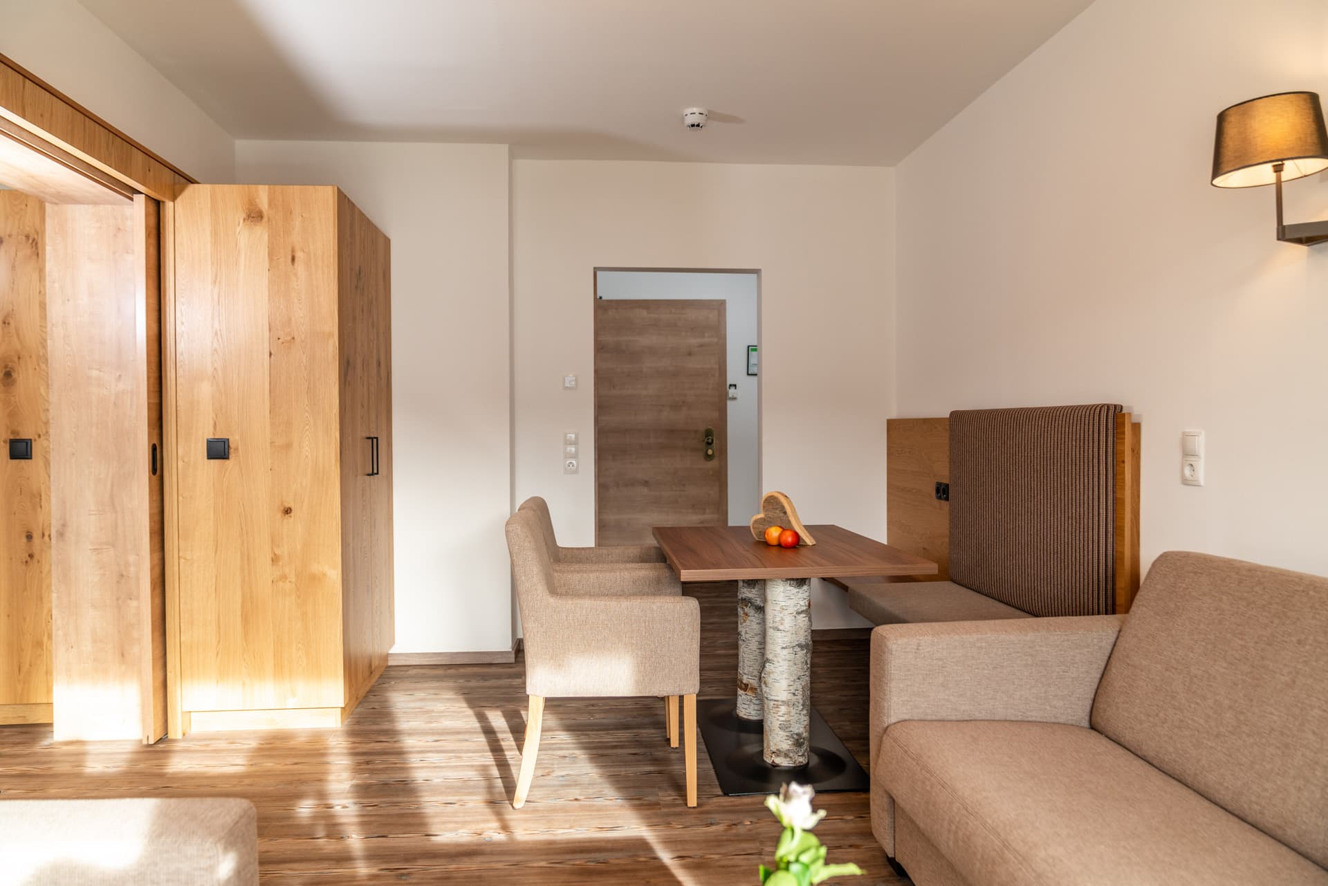Großzügiger Wohnbereich mit Sofa, Wandlampe und Essbereich im Hotel Pehab Appartement.