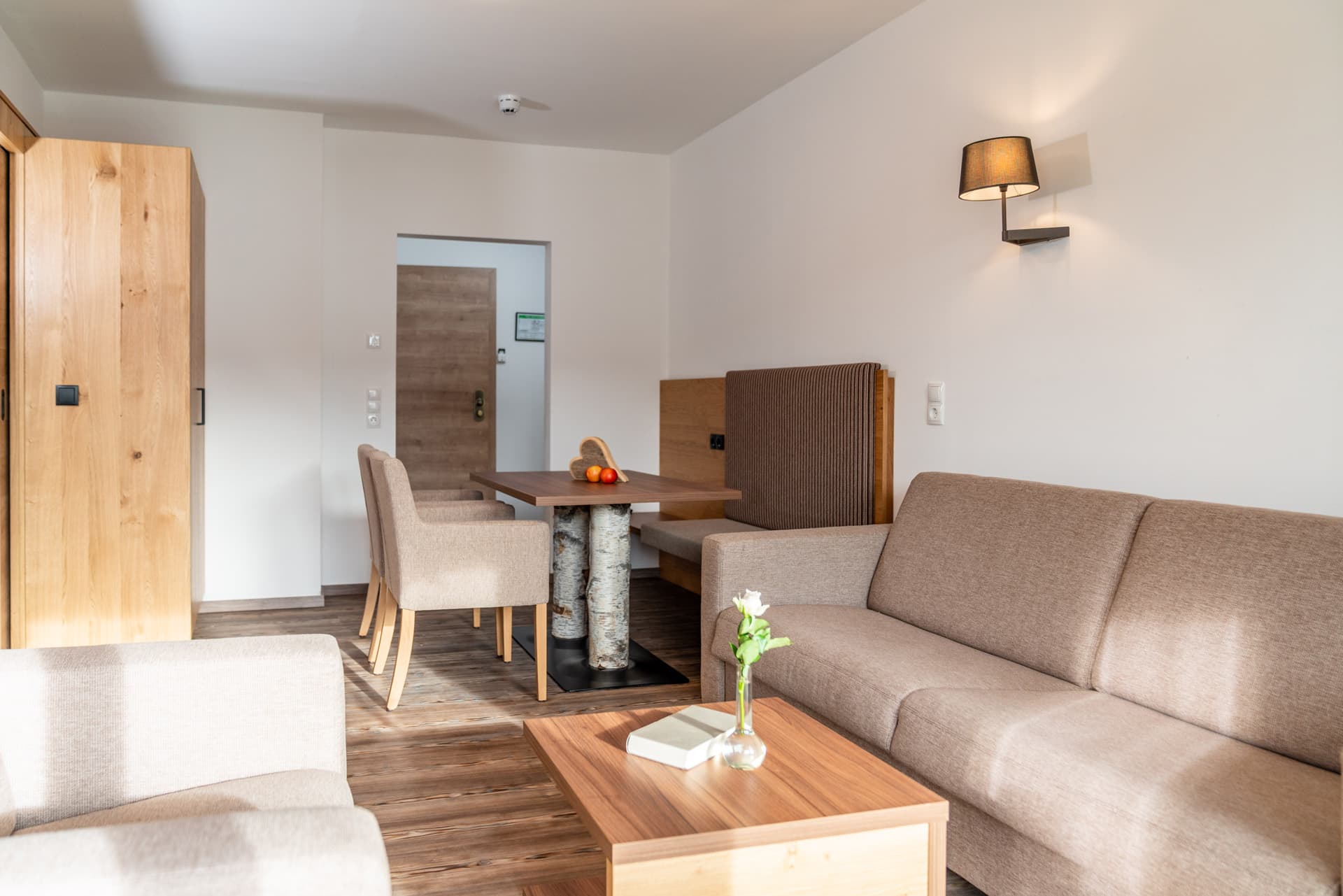 Großzügiger Wohnbereich mit Sofa, Wandlampe und Essbereich im Hotel Pehab Appartement.