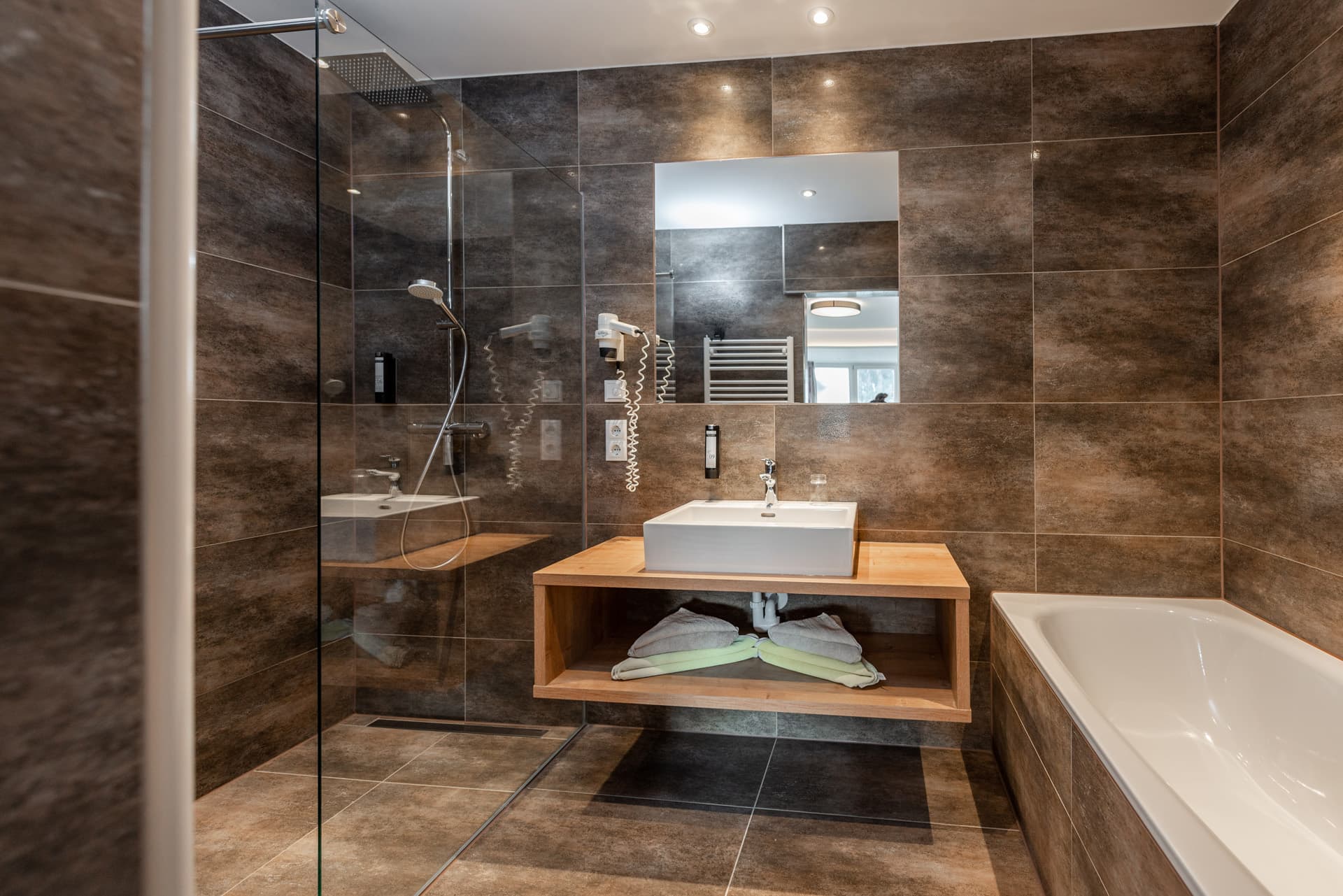 Modernes Badezimmer mit Dusche, Waschbecken und Holzdetails im Hotel Pehab.