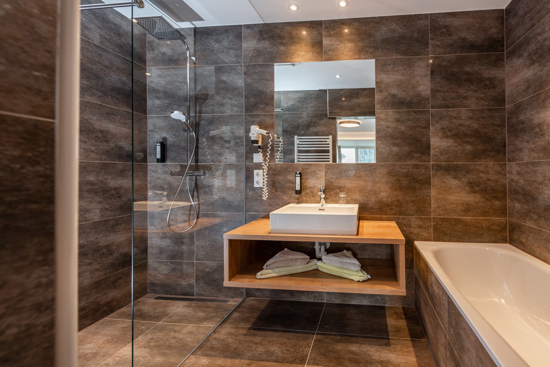 Badezimmer mit Glasdusche, hellem Waschbecken und Steinfliesen im Hotel Pehab.