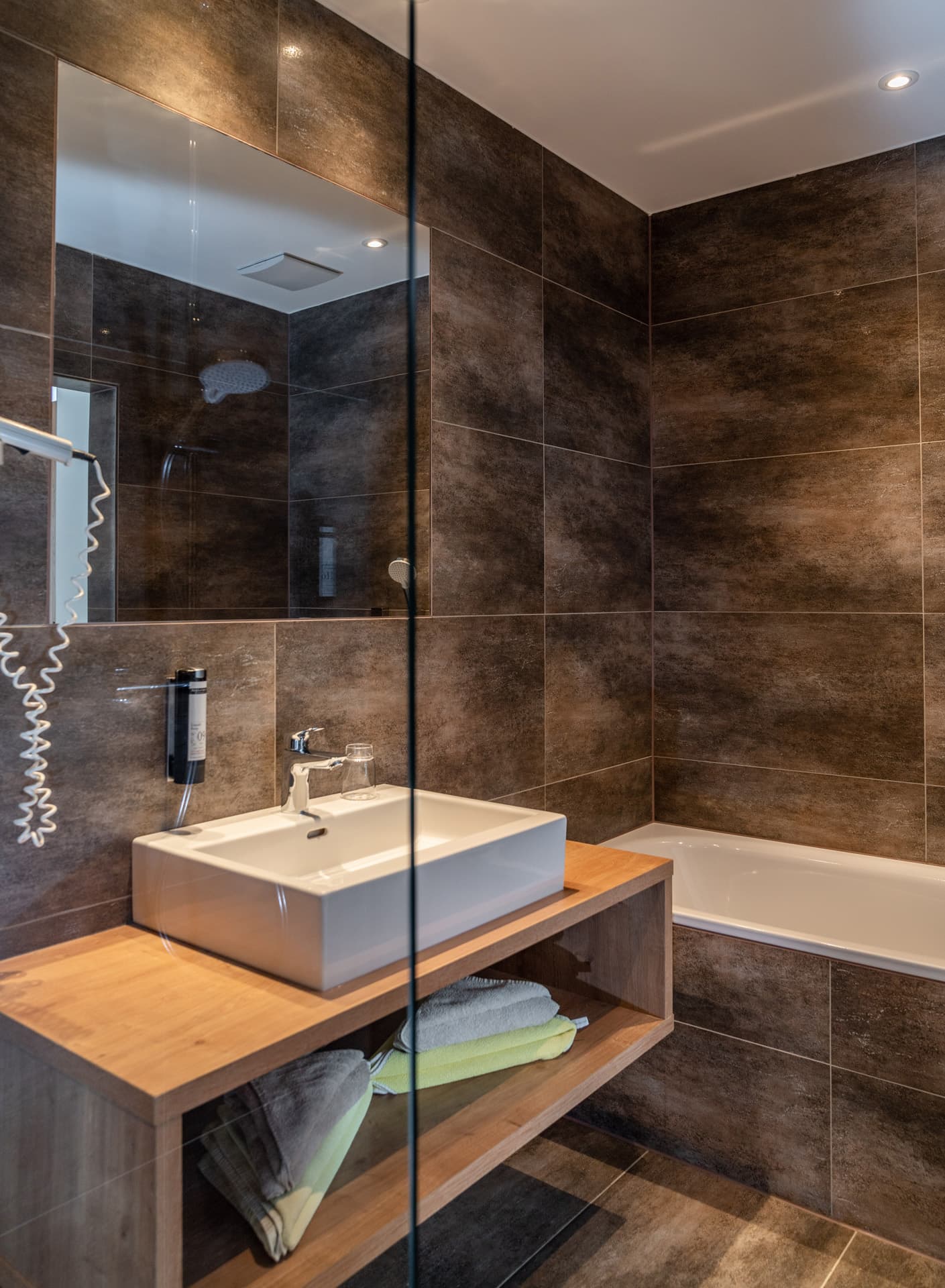 Modernes Badezimmer mit Glasdusche und edlen Steinfliesen im Hotel Pehab.