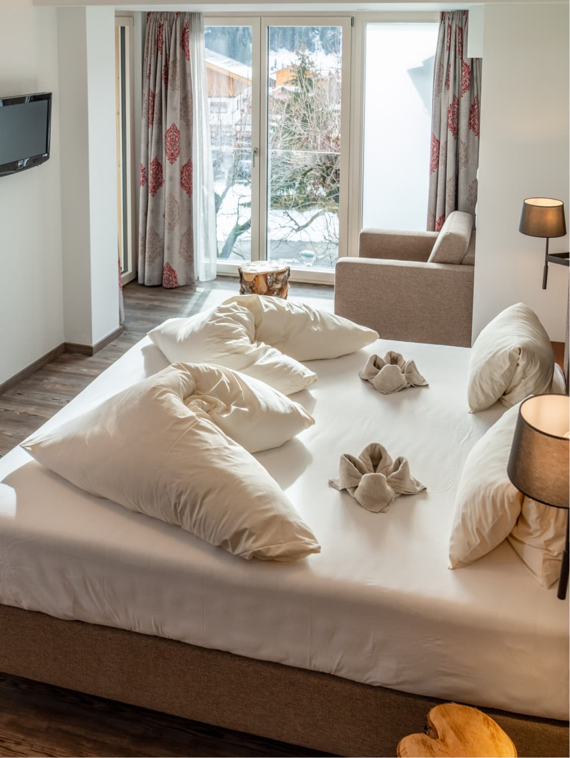 Hotel-Pehab-Zimmer mit frischer Bettdeko und Winterlandschaft vor dem Fenster.