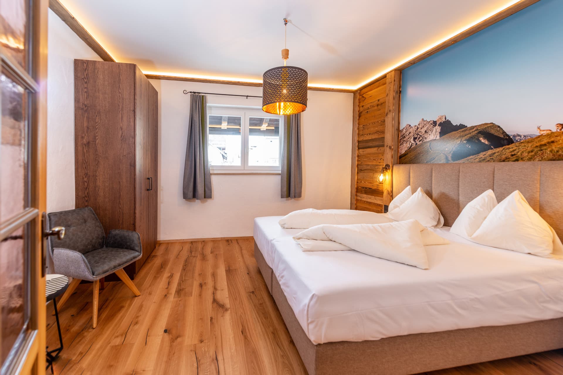 Gemütliches Doppelzimmer mit Holzelementen und warmem Lichtdesign im Hotel Pehab.