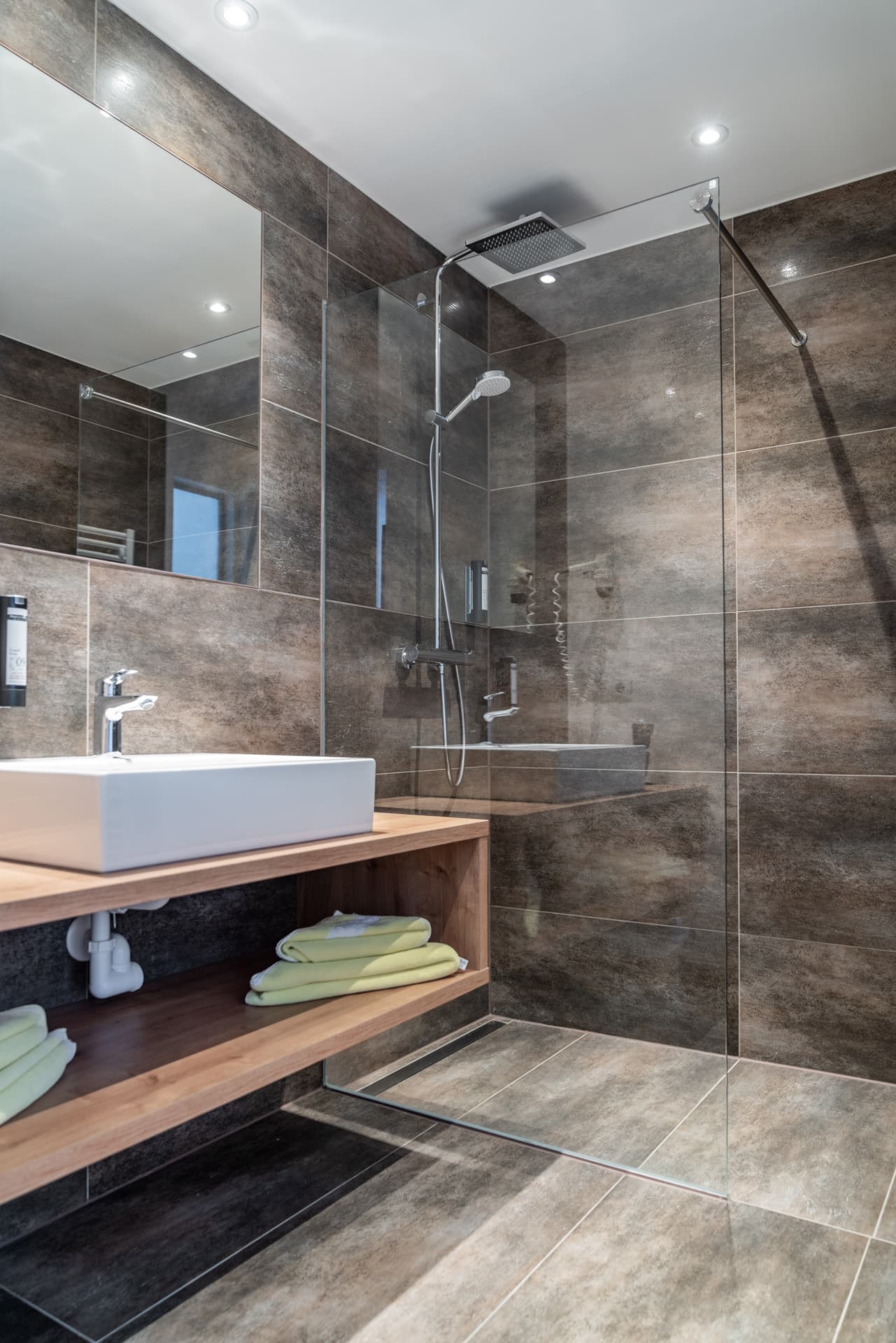 Modernes Bad mit Glasdusche und Steinfliesen im Hotel Pehab.