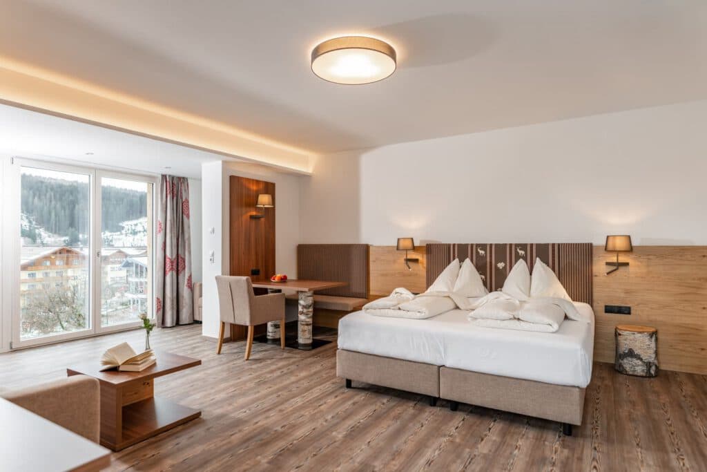 Helles Doppelzimmer mit Holzmöbeln und Sitzecke im Hotel Pehab.