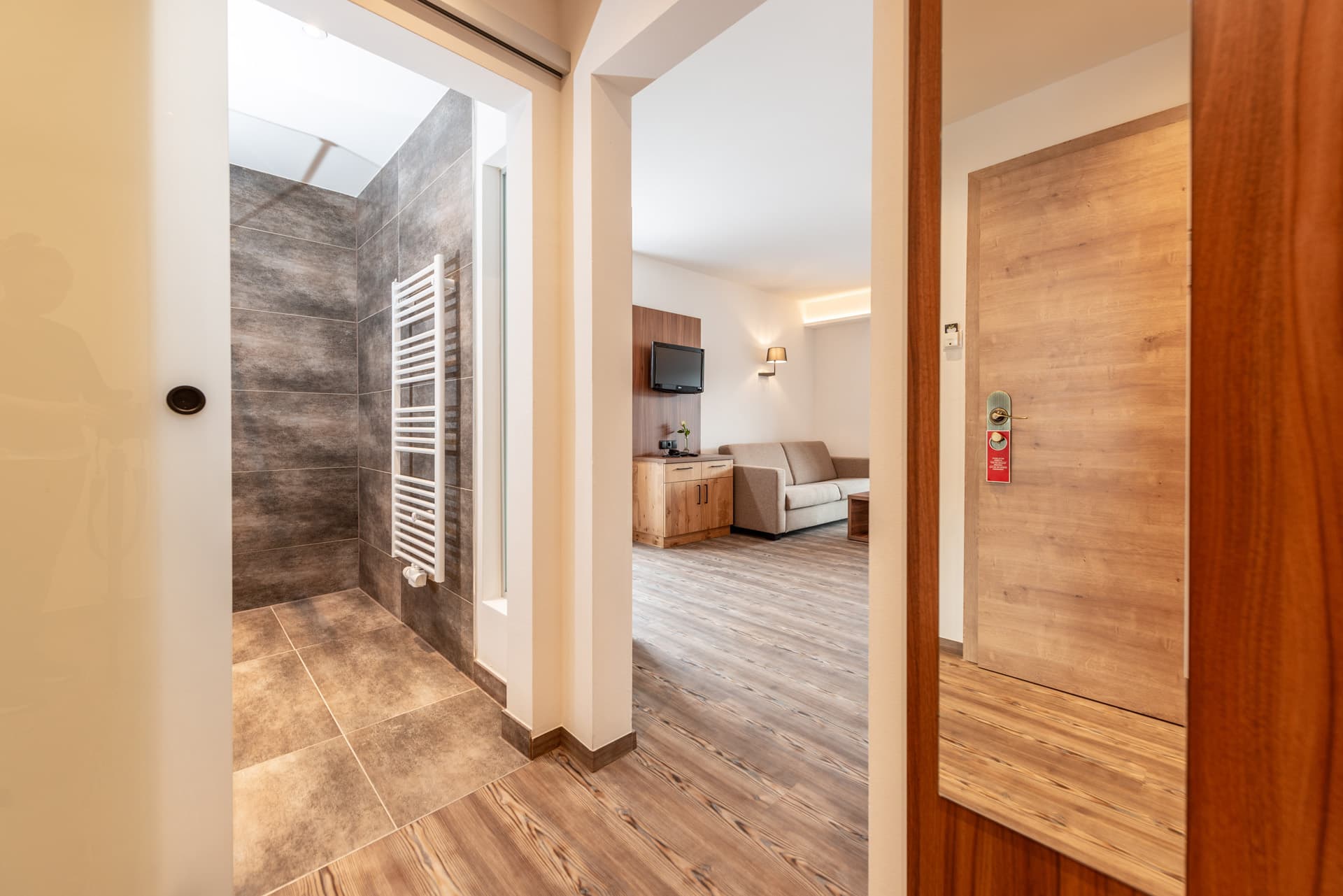 Modern ausgestattetes Bad mit Dusche, hellem Holz und Fliesen im Hotel Pehab.