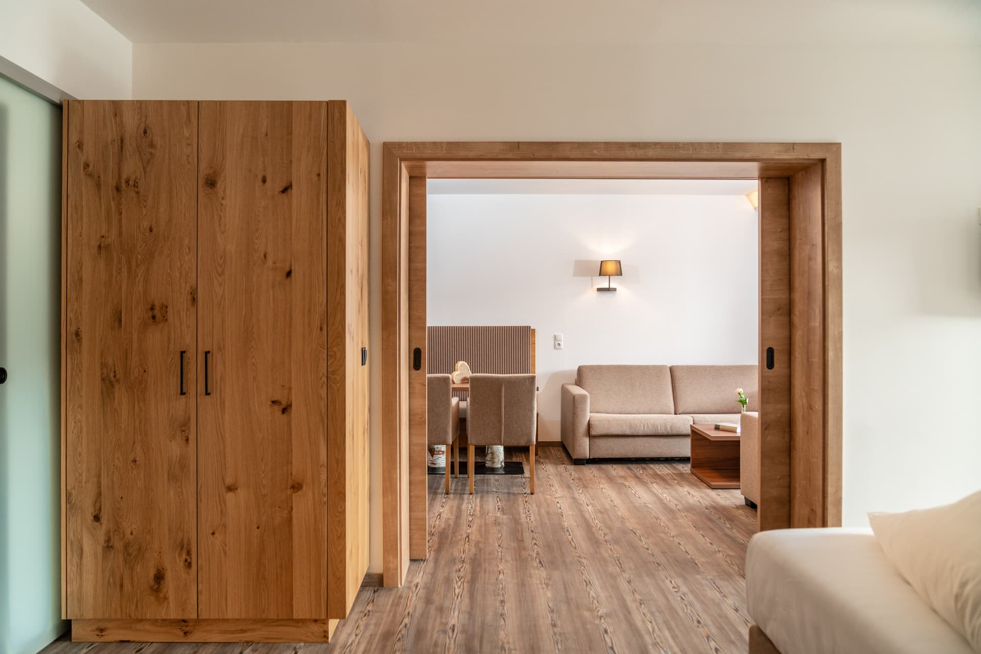 Großzügiger Wohnbereich mit Sofa, Wandlampe und Essbereich im Hotel Pehab Appartement.