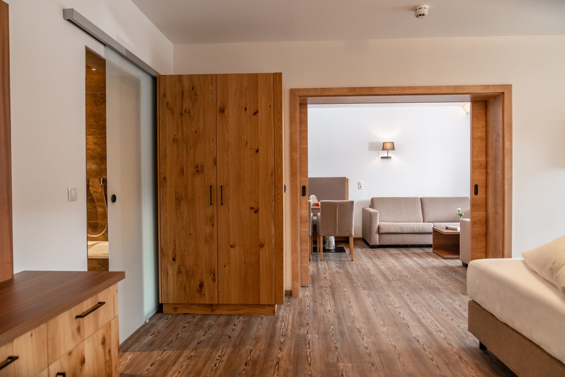 Großzügiger Wohnbereich mit Sofa, Wandlampe und Essbereich im Hotel Pehab Appartement.