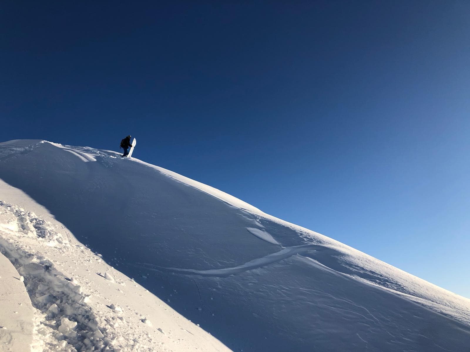 Skifahrer auf einem sonnigen Schneerücken mit tiefblauem Himmel am Dachstein.
