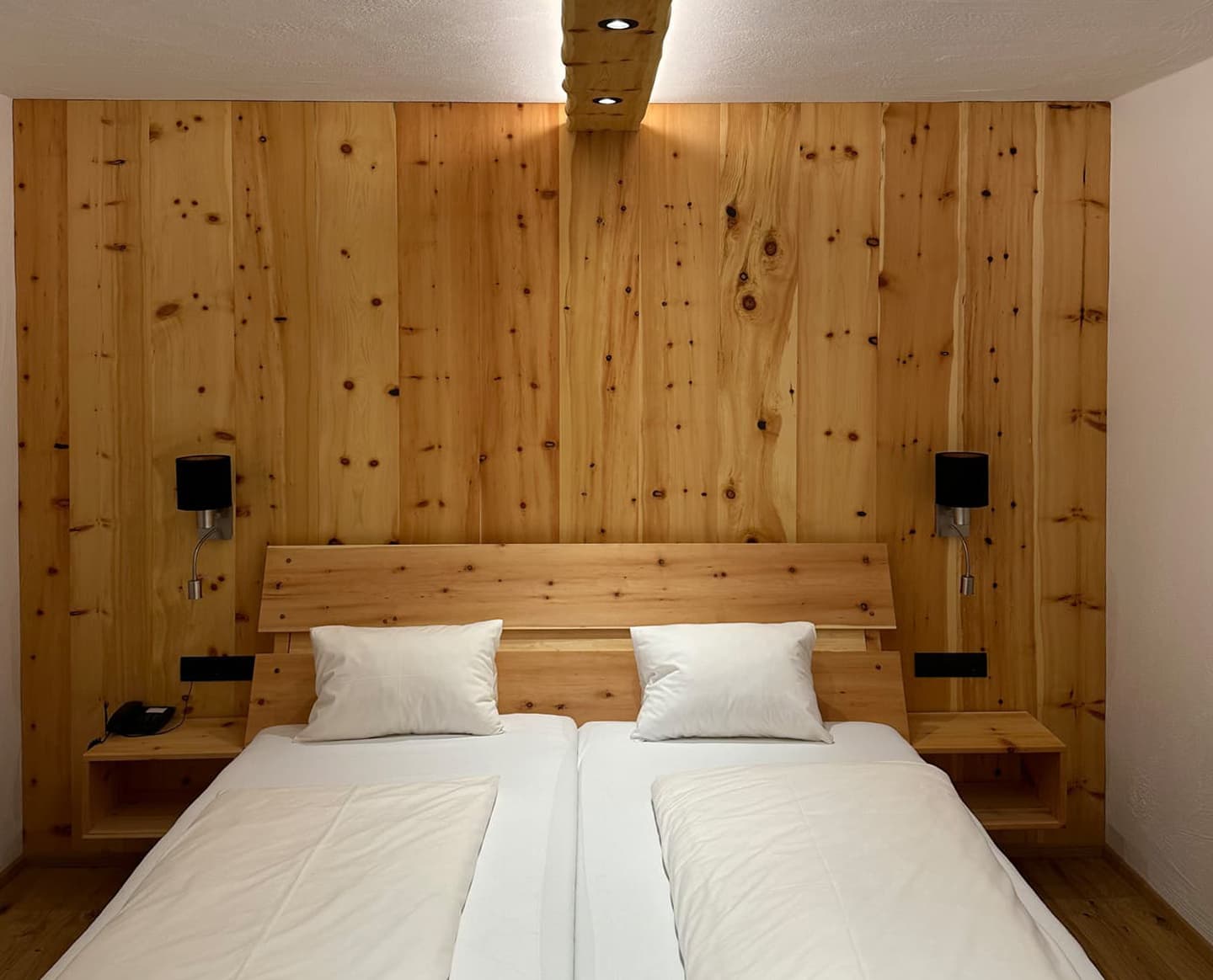 Doppelzimmer mit rustikalem Holzdesign und integriertem Beleuchtungselement.
