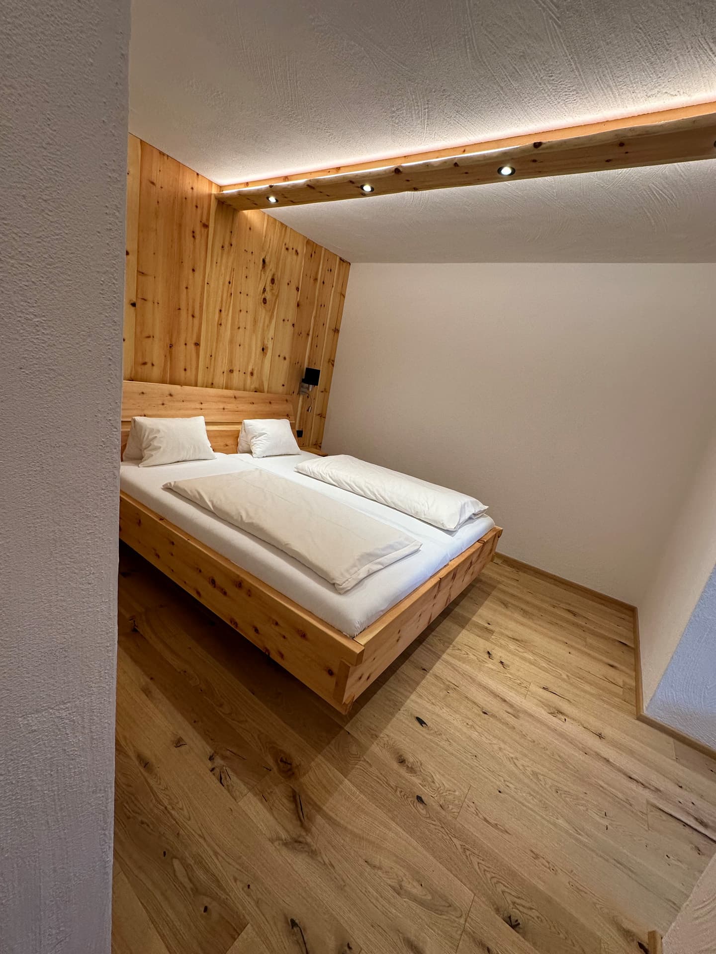 Doppelzimmer mit Holzrahmenbett und warmem Licht im Hotel Pehab.