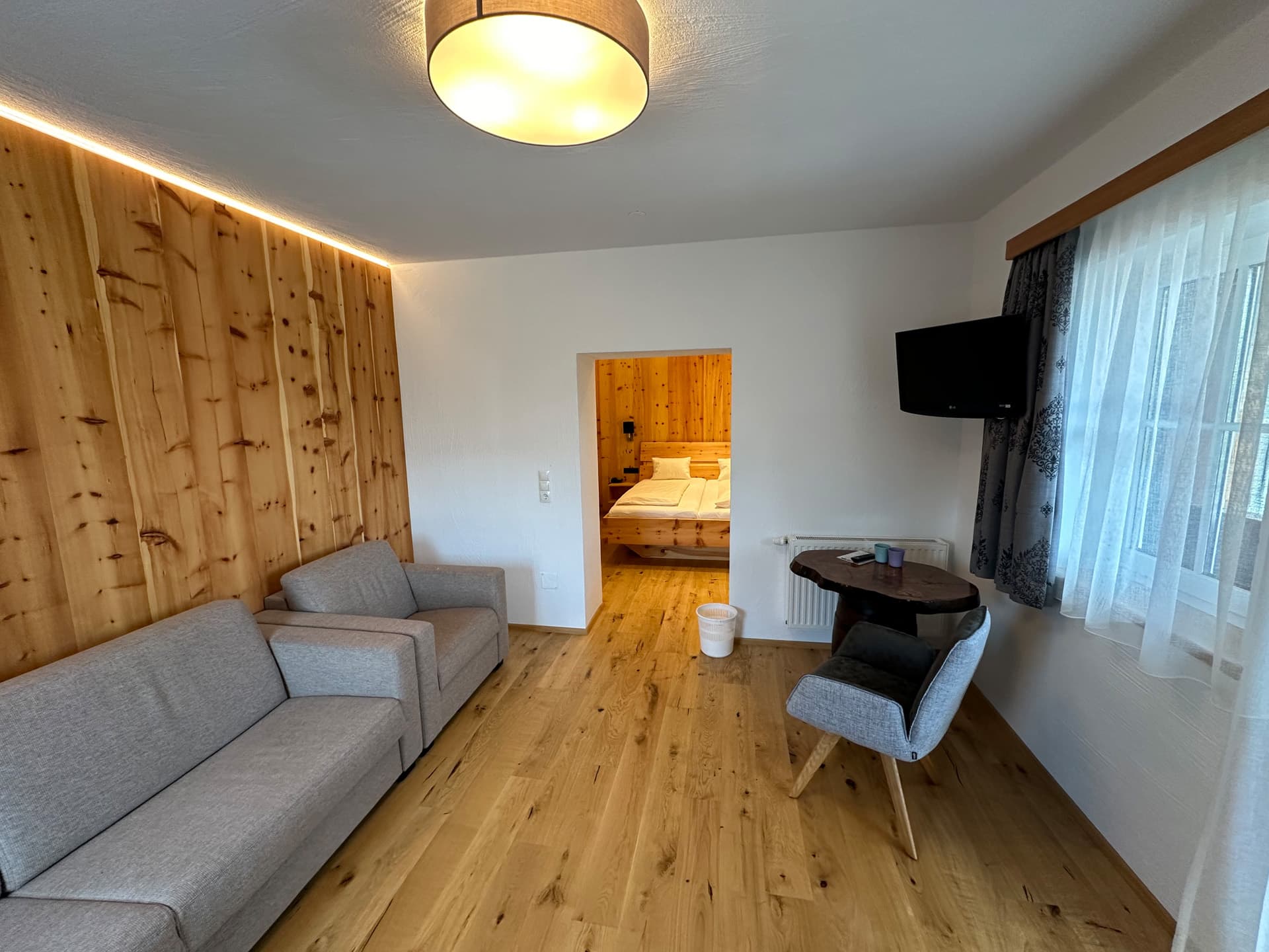 Wohnzimmer mit Sofa, hellem Design und großen Fenstern im Hotel Pehab.