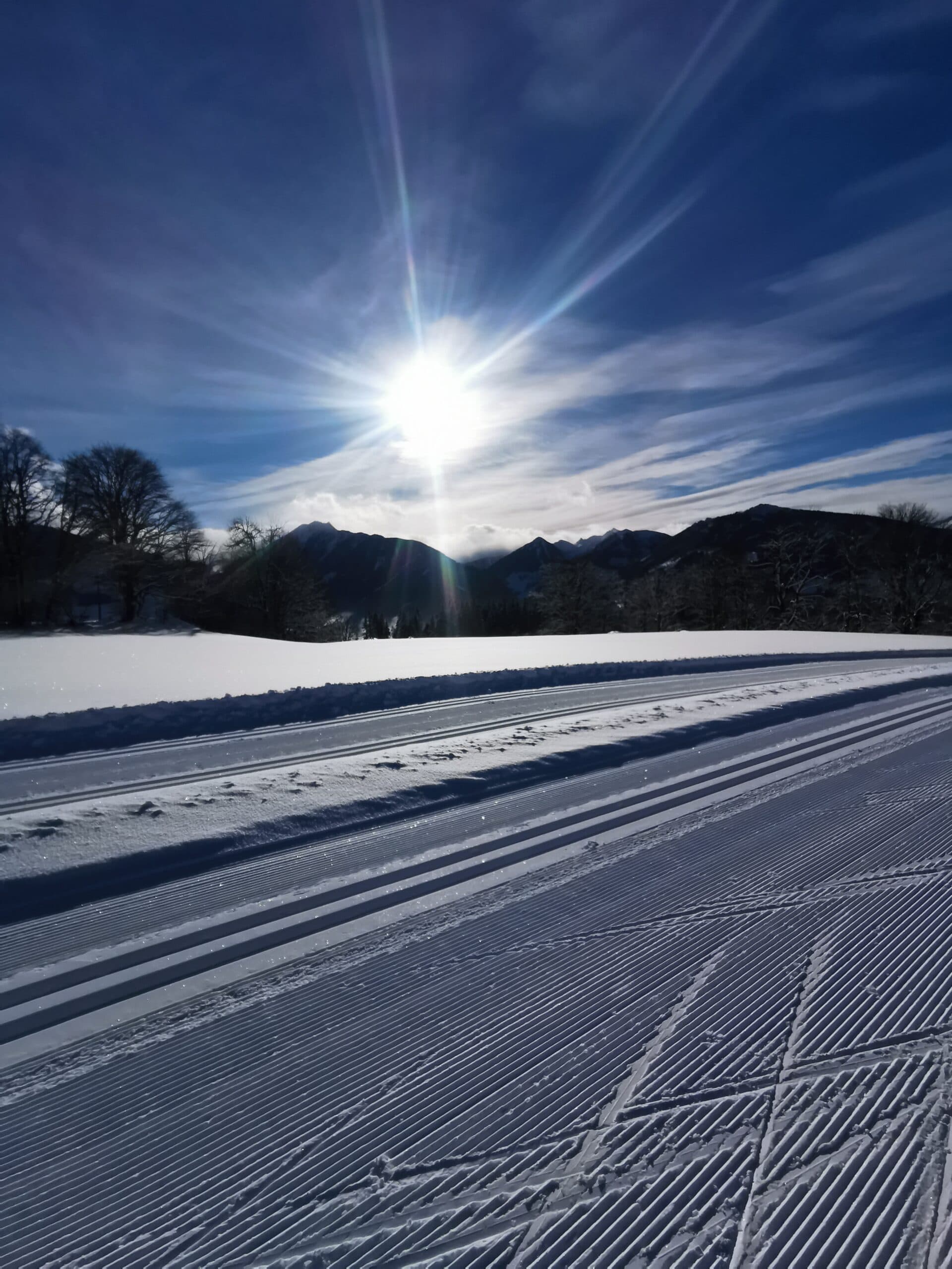 Sonnenlicht über frisch gespurter Langlaufloipe in Ramsau am Dachstein, nahe dem Hotel Pehab.
