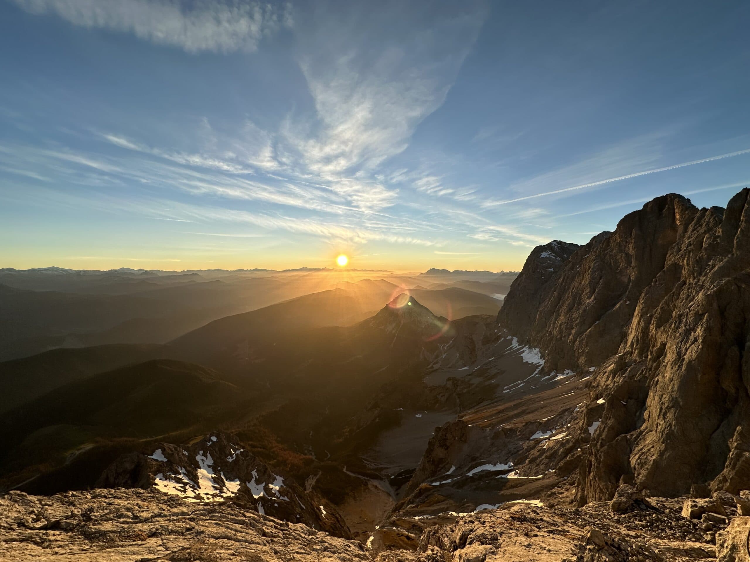 Almhang im Gegenlicht mit Sonne über den Bergen bei Schladming.