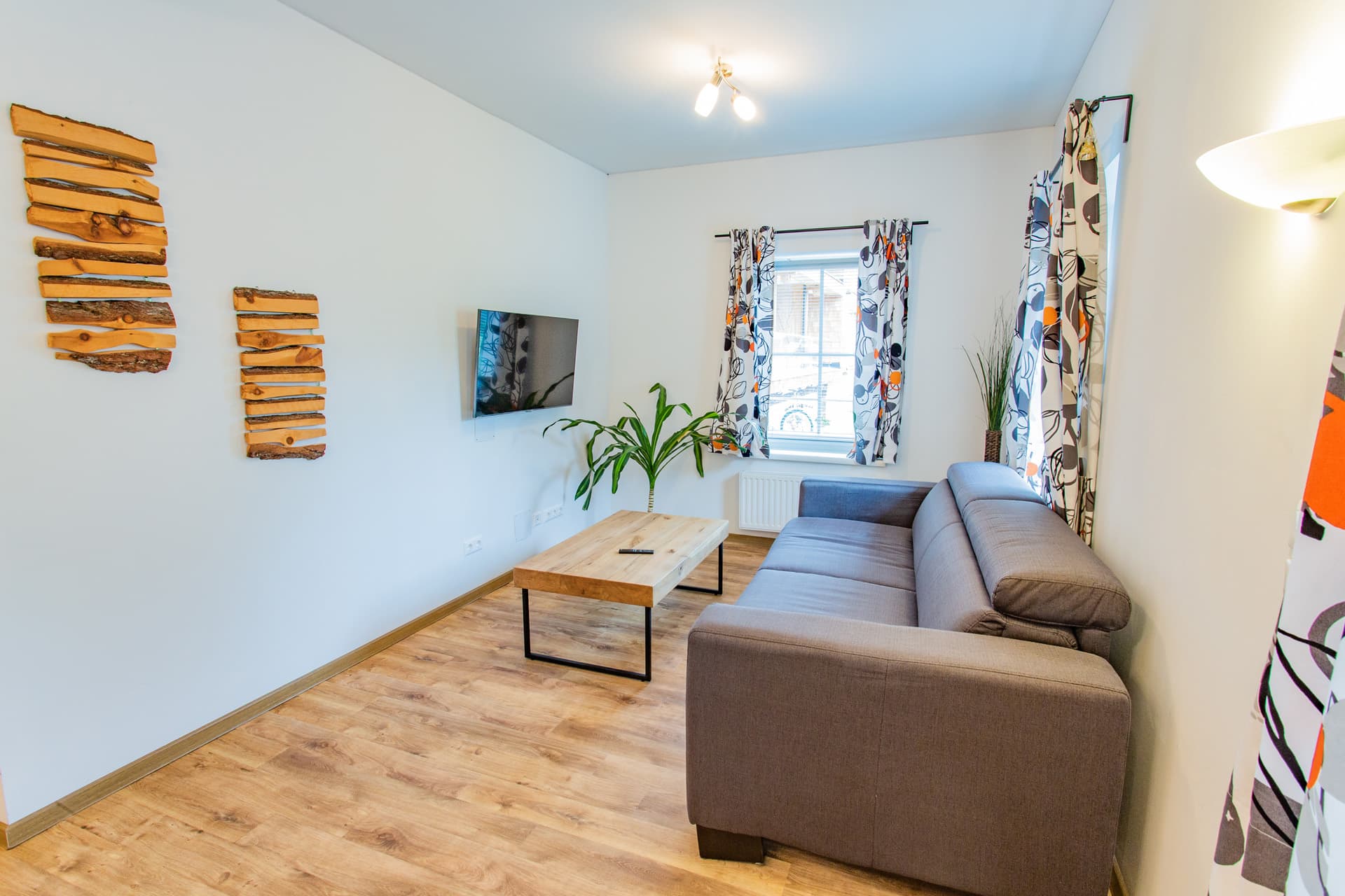 Wohnzimmer mit Sofa und hellem Holzboden im Hotel Pehab Appartement.