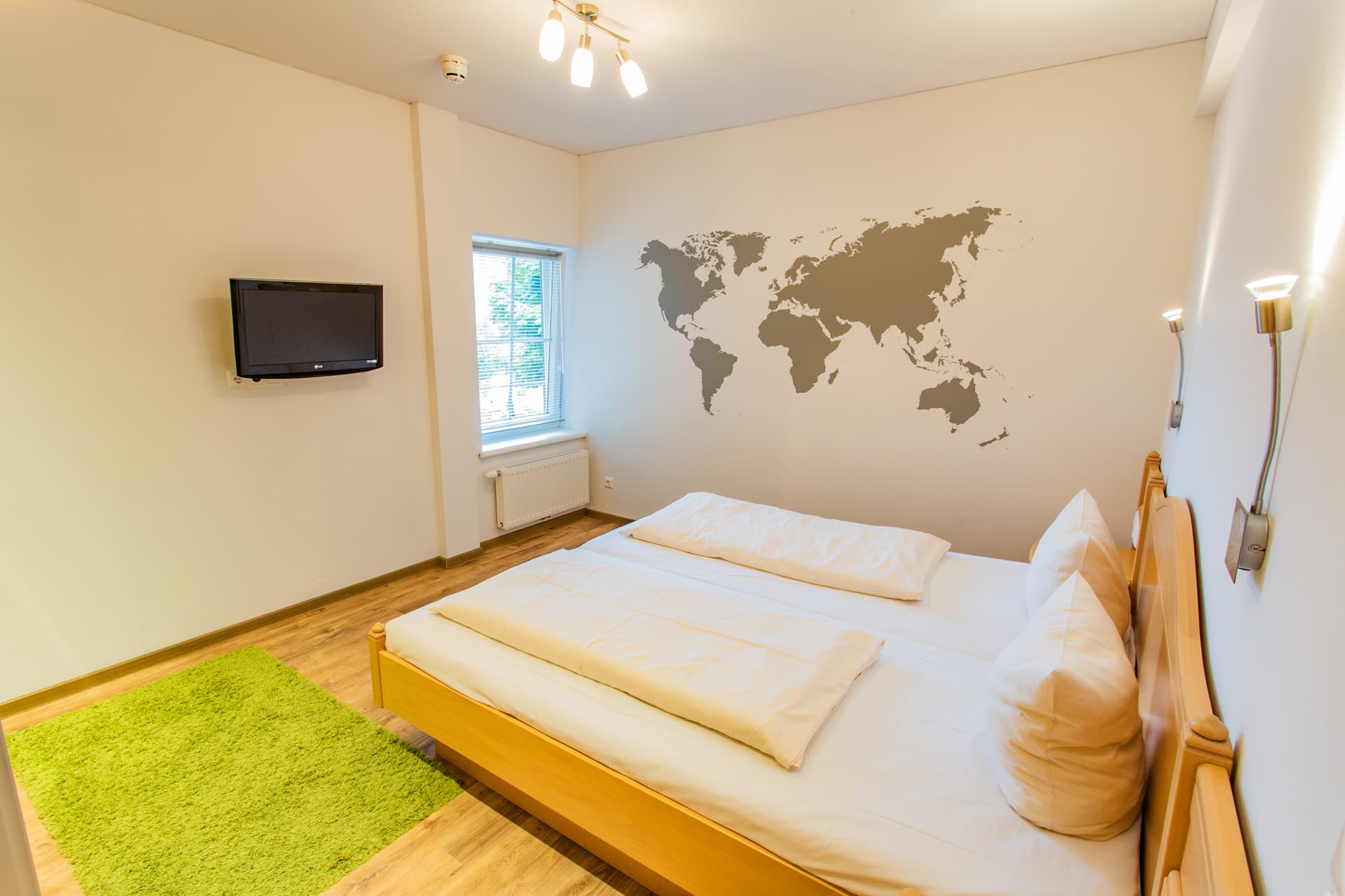 Schlafbereich mit Doppelbett und Weltkarten-Dekowand im Hotel Pehab.