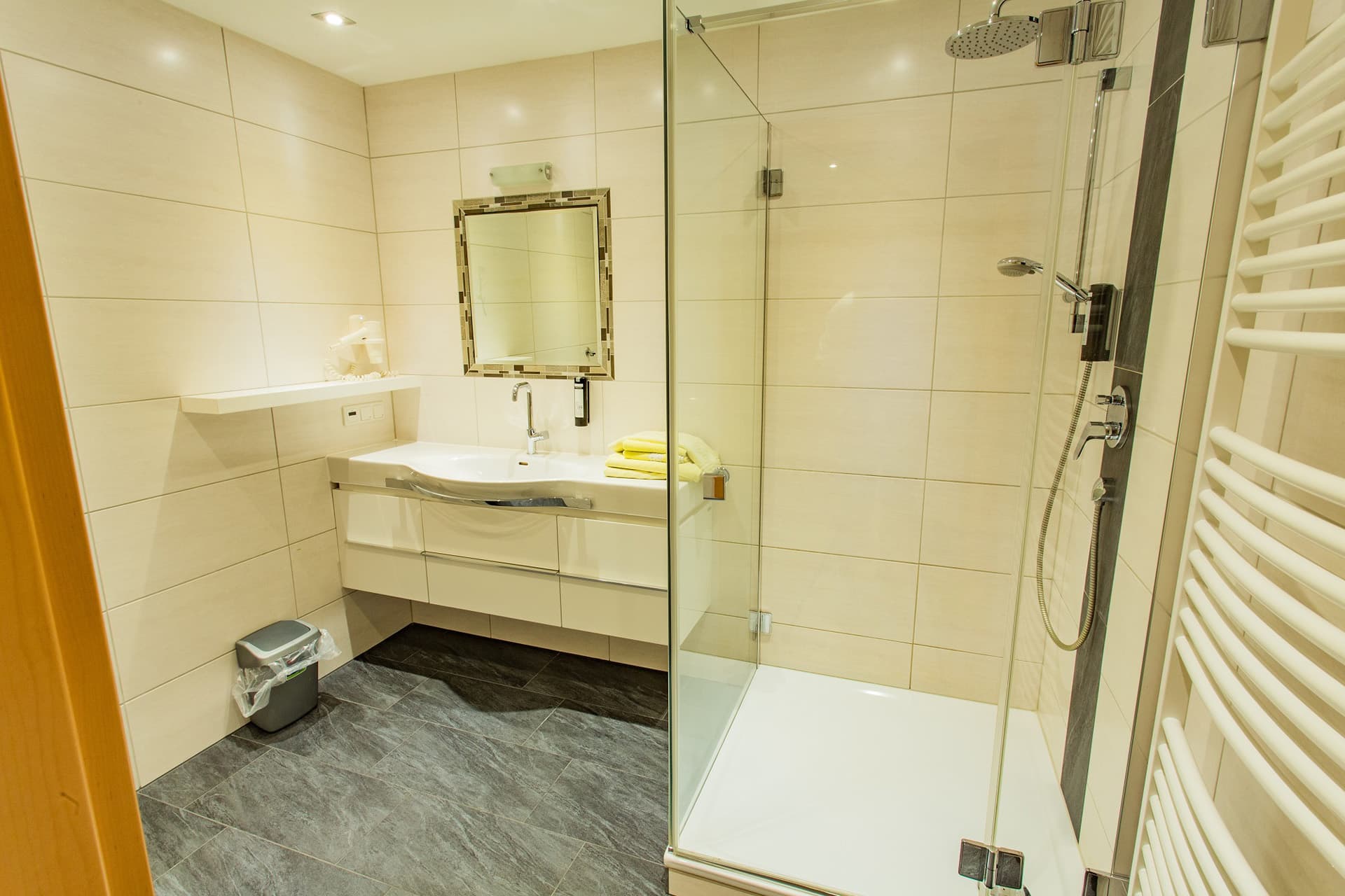 Badezimmer mit Dusche und großem Spiegel im Hotel Pehab.