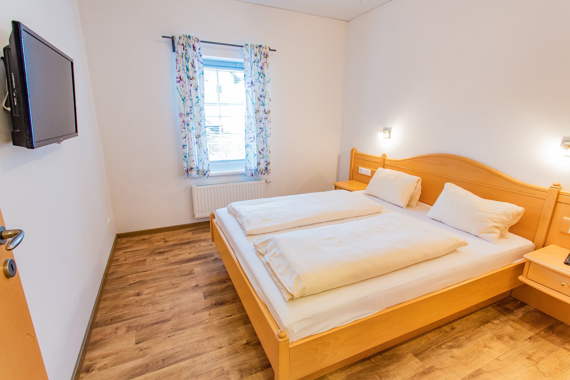 Doppelzimmer mit Holzbett und hellen Wänden im Hotel Pehab.