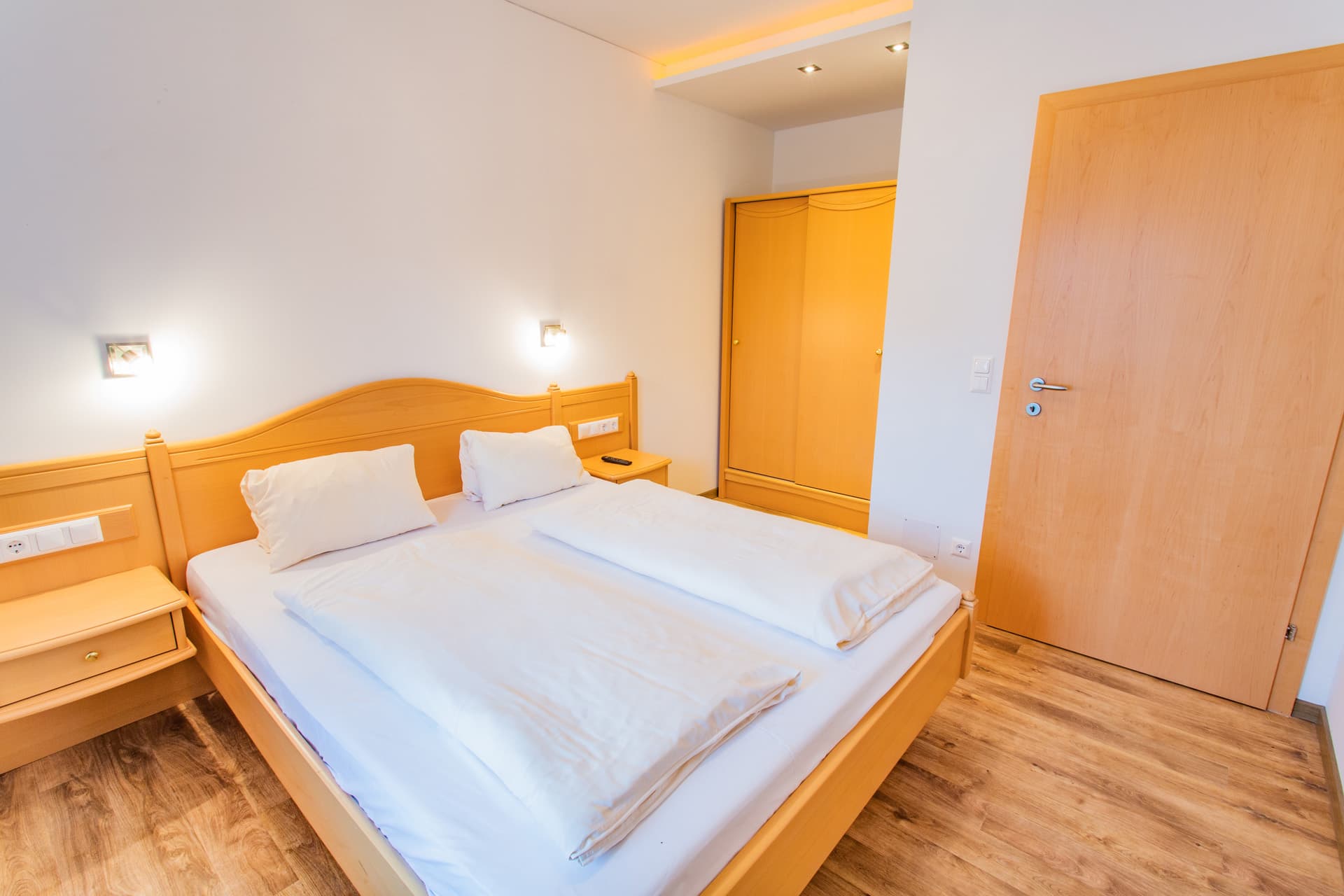 Doppelzimmer mit Holzbett und hellen Wänden im Hotel Pehab.