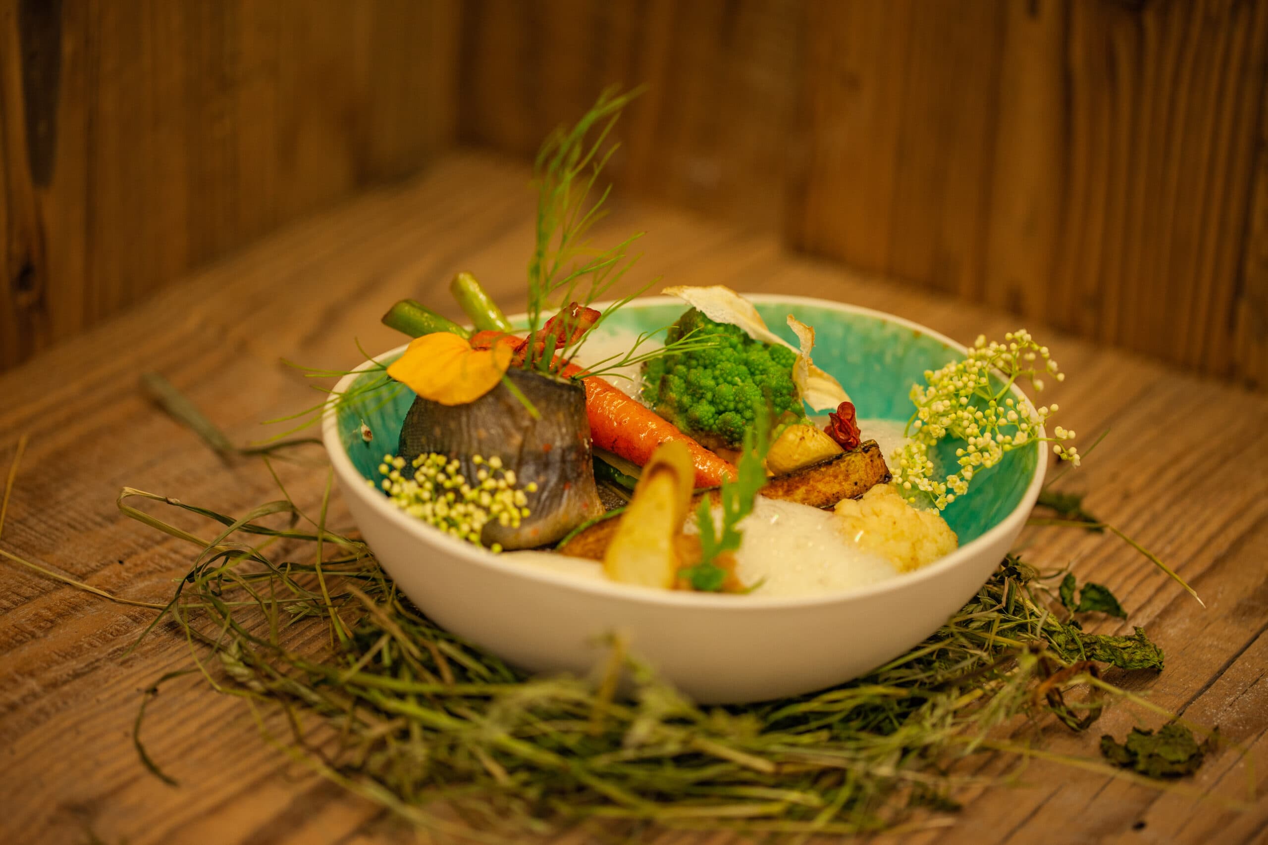 Gourmetgericht mit Kräutern, Gemüse und essbaren Blüten im Hotel Pehab.