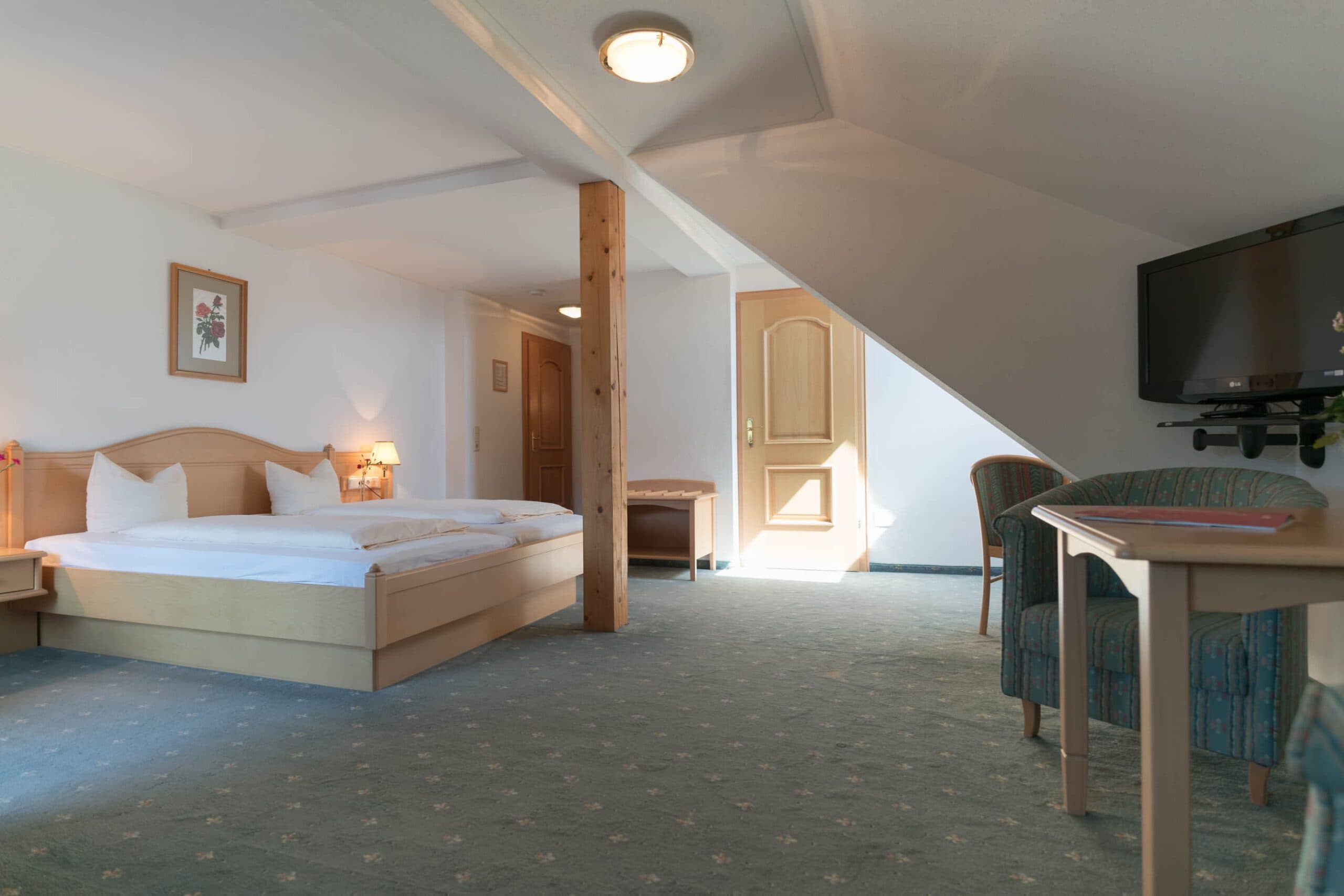 Modern ausgestattetes Bad mit Dusche, hellem Holz und Fliesen im Hotel Pehab.