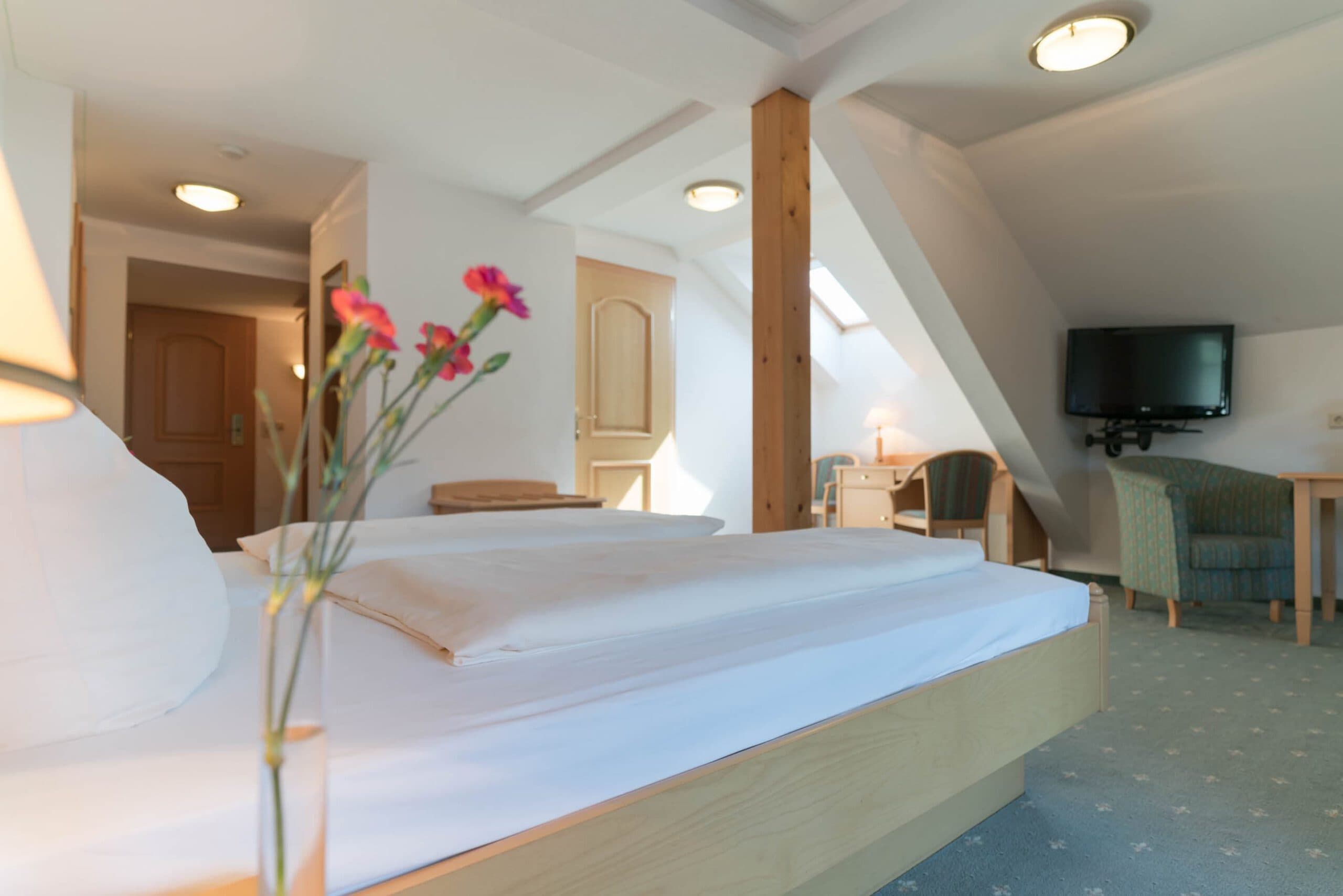 Doppelzimmer mit Blumen-Dekoration und Dachschräge im Hotel Pehab.