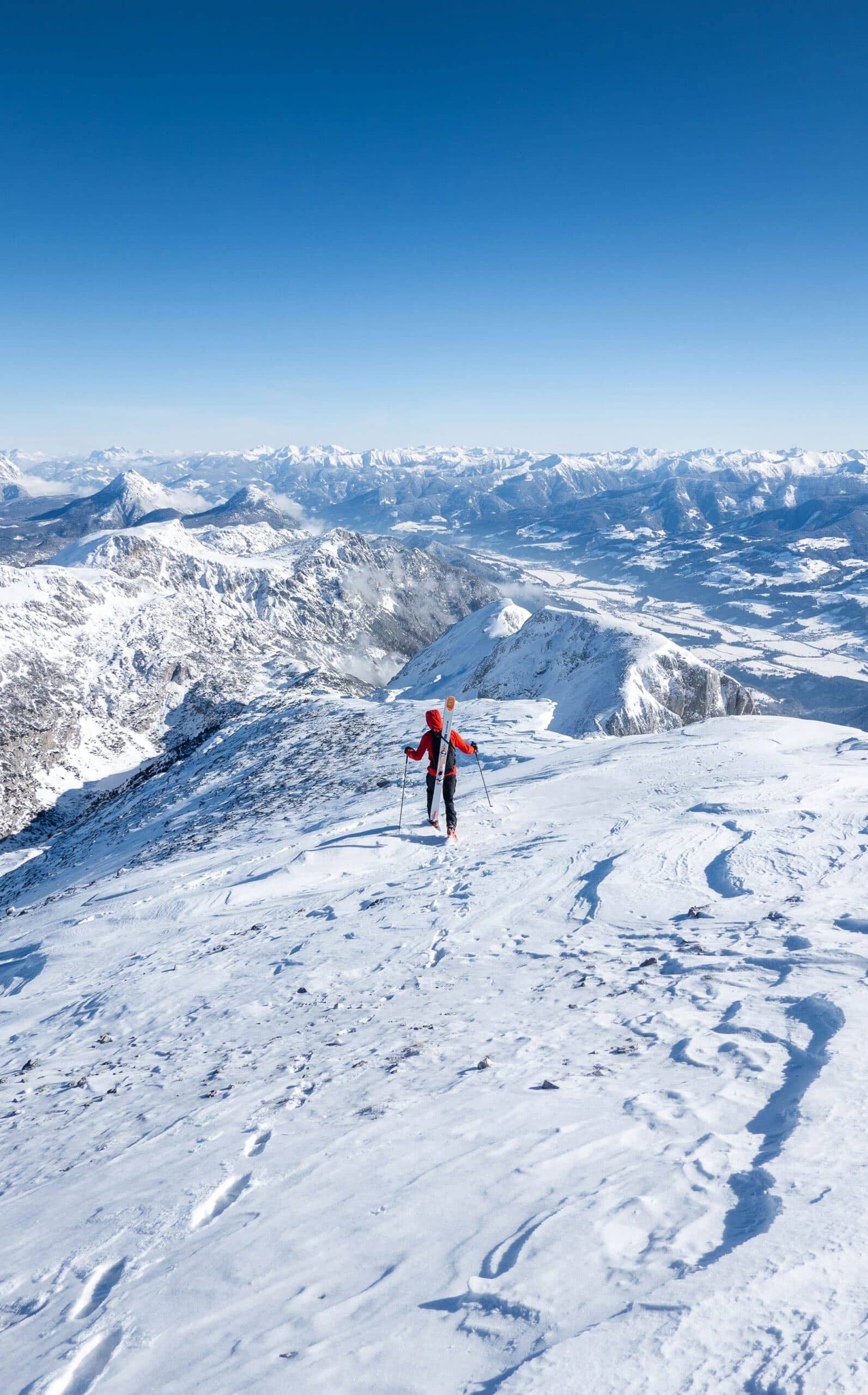 Wintersportler auf Bergkamm mit Fernblick über die verschneite Alpenlandschaft.