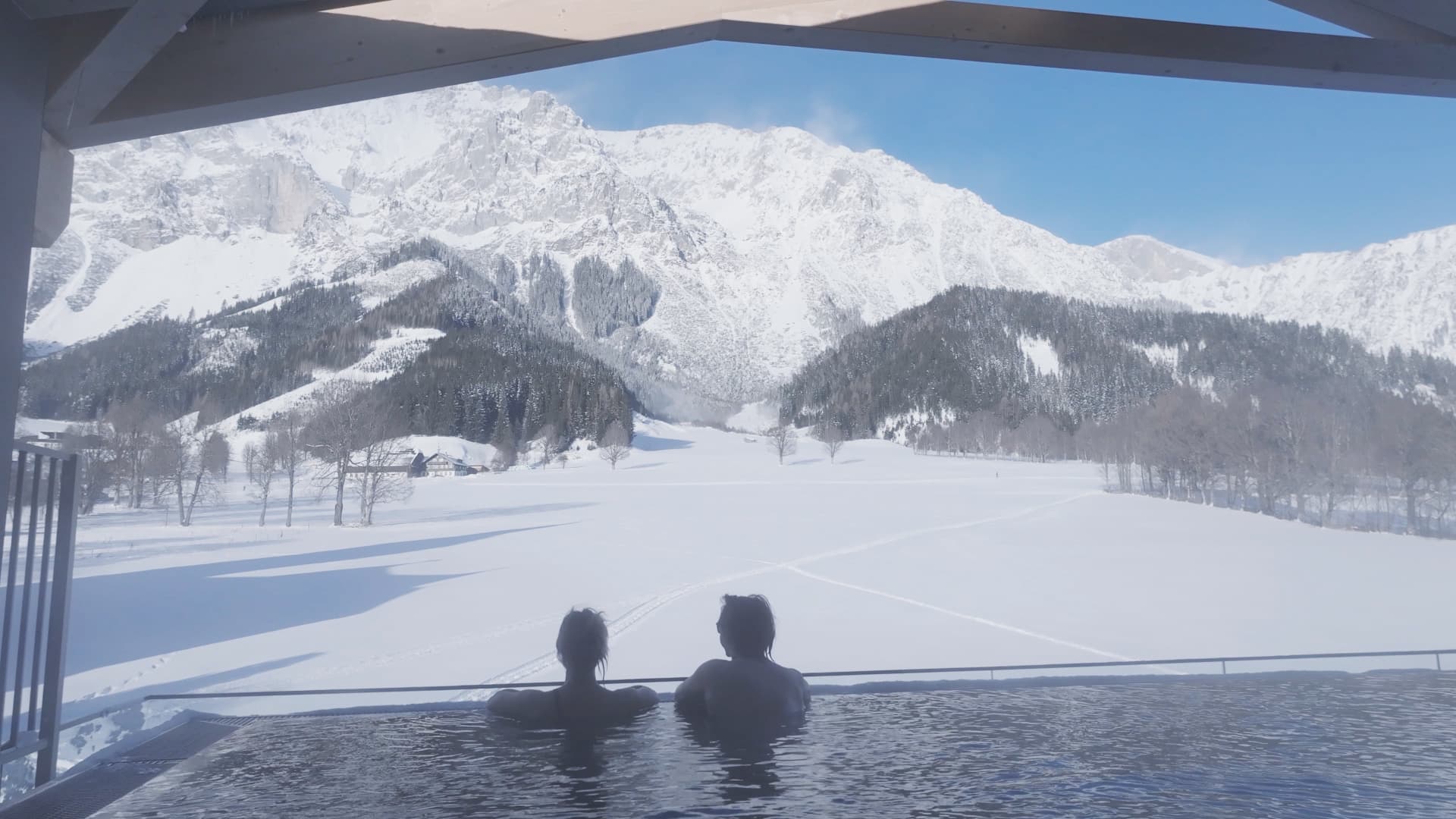 Infinity-Pool mit Bergpanorama und verschneiter Winterlandschaft