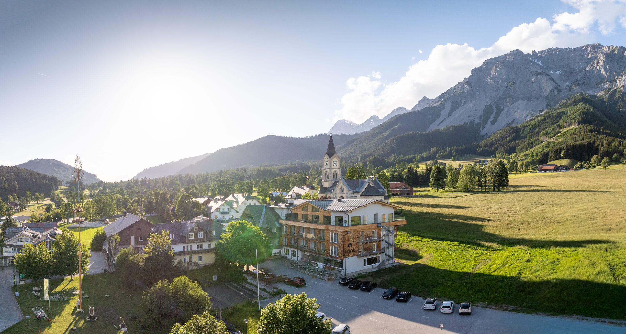 Ramsau am Dachstein mit Kirche und Dachsteinmassiv im Sommer aus der Luft